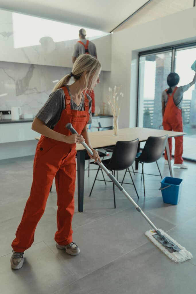 Three people cleaning Sydney Apartment Cleaning team in red overalls mopping and sanitizing a modern home interior.